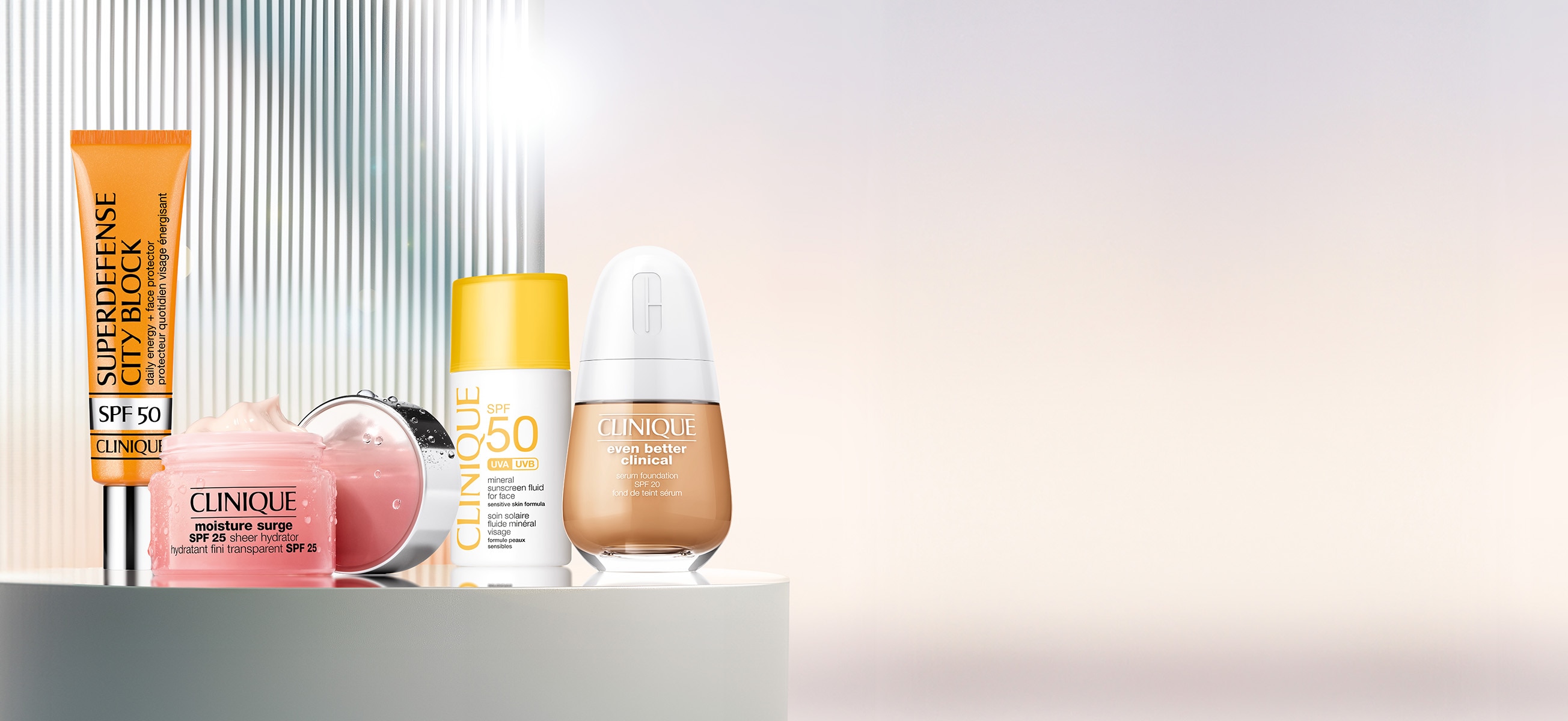 Selection of best selling Clinique SPF products on a grey plinth in front of a brightly lit, summery background