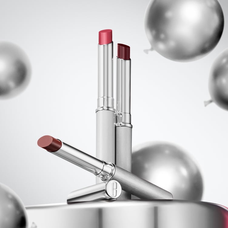 Selection of new brow and eye products dynamically placed on a glass shelf, in a brightly lit studio setting